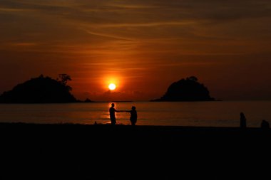 Filipinler, Palawan 'da güzel bir plajda gün batımında el ele tutuşan çift.