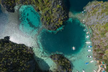 Kayangan Gölü yakınlarındaki Coron Adası 'nın göl manzarası güneşli bir günde tipik Filipinli teknelerle dolu.