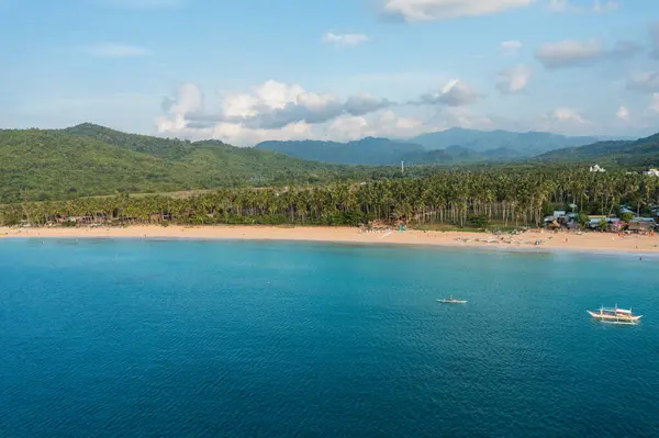 Gün batımında Nacpan sahilinden hava manzarası, insanlarla dolu güzel palmiye ağaçları ve birkaç tekne..