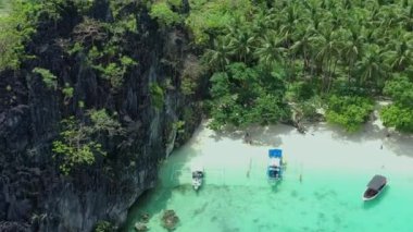 Tipik Filipinli banka tekneleri ve tatilin tadını çıkaran insanların bulunduğu Paradisiacal Seven Commando plajının havadan görüntüsü..