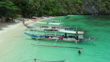 Tipik Filipinli banka tekneleri ve tatilin tadını çıkaran insanların bulunduğu Paradisiacal Seven Commando plajının havadan görüntüsü..