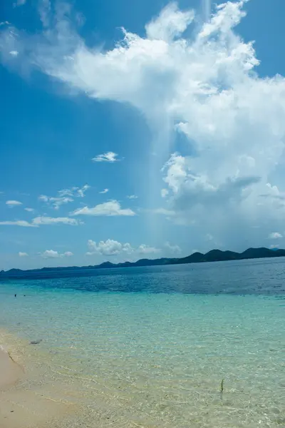 Paradise beach with transparent waters with a curtain of water in the background, in the Philippines.