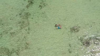 Filipinler, Palawan 'da turkuaz mavi sularda tropikal bir sahilde eğlenen güzel bir çift.