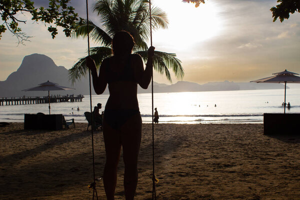 Силуэт женщины, качающейся на закате на пляже Лио, Палаван, Филиппины.