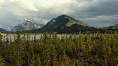 Kanada Banff yakınlarında bulutlu bir günde, sonbaharda, çam ağaçlarıyla dolu Vermilion Gölleri ve Sülfür Dağı 'nın güzel hava manzarası..