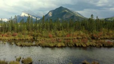 Kanada Banff yakınlarında bulutlu bir günde, sonbaharda, çam ağaçlarıyla dolu Vermilion Gölleri ve Sülfür Dağı 'nın güzel hava manzarası..