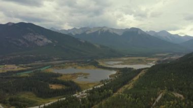 Kanada Banff yakınlarında bulutlu bir günde, sonbaharda, çam ağaçlarıyla dolu Vermilion Gölleri ve Sülfür Dağı 'nın güzel hava manzarası..