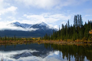 Kanada Banff yakınlarında bulutlu bir günde, sonbaharda, çam ağaçlarıyla dolu Vermilion Gölleri ve Sülfür Dağı 'nın güzel hava manzarası..