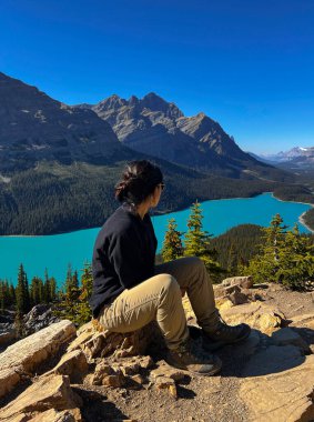 Güneş gözlüklü güzel kadın güneşli bir günde Kanada 'da Peyto Gölü' nde yürüyüş yaptıktan sonra dinleniyor..