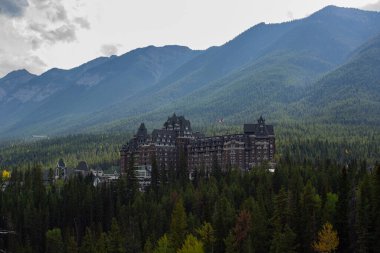 Kanada 'da bulutlu bir günde Banff Springs Oteli' nin ağaçlarının arasına bak..