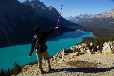Yürüyüş sopasıyla gezen kadın. Güneşli bir sonbahar gününde güzel Peyto Gölü 'nde turkuaz suyla.