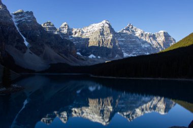 Güneşli bir sonbahar gününde Moraine Gölü yakınlarındaki On Tepe Vadisi 'nde dağda kar var. Güneşli bir sabahta dağların güzel yansıması..