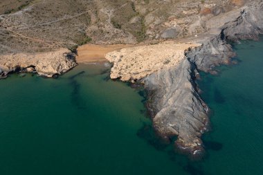 İspanya 'nın Cabo de Palos Murcia kentindeki turkuaz suları ve büyük kayaları ile Cala Dorada' nın küçük kumsalının güzel hava manzarası.