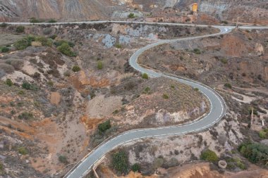 Aerial view of a beautiful S-shaped road of an abandoned mine with its towers in a desert area in La Union, Murcia. clipart