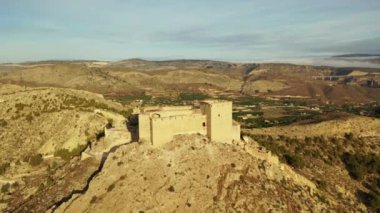 İspanya, Murcia bölgesindeki Mula 'nın etkileyici ortaçağ şatosunun sarp ve kayalık bir tepe üzerindeki hava manzarası.