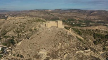 İspanya, Murcia bölgesindeki Mula 'nın etkileyici ortaçağ şatosunun sarp ve kayalık bir tepe üzerindeki hava manzarası.