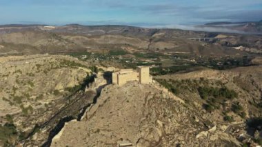 İspanya, Murcia bölgesindeki Mula 'nın etkileyici ortaçağ şatosunun sarp ve kayalık bir tepe üzerindeki hava manzarası.