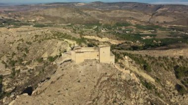 İspanya, Murcia bölgesindeki Mula 'nın etkileyici ortaçağ şatosunun sarp ve kayalık bir tepe üzerindeki hava manzarası.