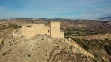 İspanya, Murcia bölgesindeki Mula 'nın etkileyici ortaçağ şatosunun sarp ve kayalık bir tepe üzerindeki hava manzarası.