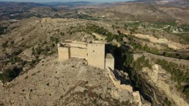 İspanya, Murcia bölgesindeki Mula 'nın etkileyici ortaçağ şatosunun sarp ve kayalık bir tepe üzerindeki hava manzarası.
