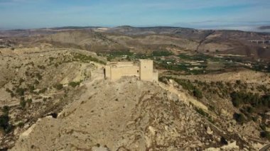 İspanya, Murcia bölgesindeki Mula 'nın etkileyici ortaçağ şatosunun sarp ve kayalık bir tepe üzerindeki hava manzarası.