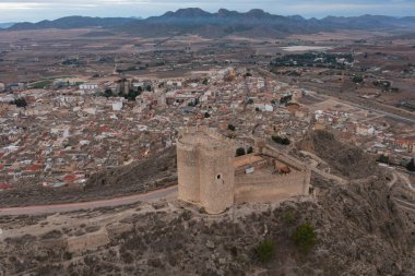 Jumilla Kalesi, Murcia, İspanya, arka planında kule ve ortaçağ duvarları olan Jumilla şehri ve bulutlu bir gün.