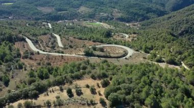 Katalonya, İspanya 'da çamlarla kaplı dağlar arasındaki mükemmel kıvrımlarla dolu dolambaçlı kırsal yolun inanılmaz hava manzarası..