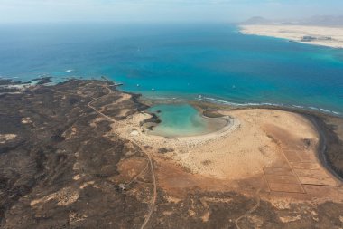 Lobos, Kanarya Adaları 'ndaki La Concha Sahili' nin insansız hava aracı görüntüsü turkuaz suları, geleneksel tuz düzlükleri ve yakındaki Fuerteventura volkanik manzarası..