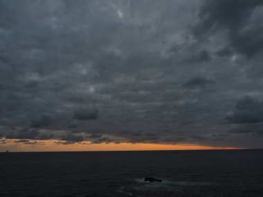 Uçurumdan gün doğumu manzarası bulutlarla dolu gökyüzü ve güneşin kıpkırmızı deniz ufku.