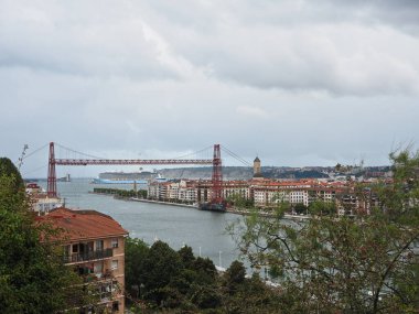Halkımızın üzerinde asma köprü olan bir manzara ve bulutlu bir günde ufukta bir yolcu gemisi.