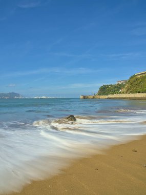 Sahilde kayalar ve dalgalar kıyıya vuruyor.