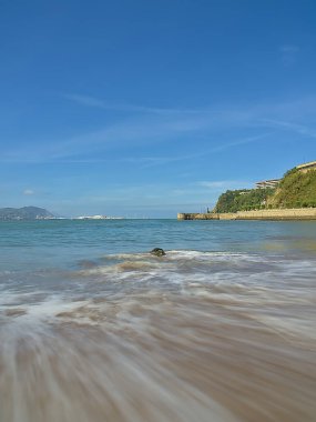 Sahilde kayalar ve dalgalar kıyıya vuruyor.