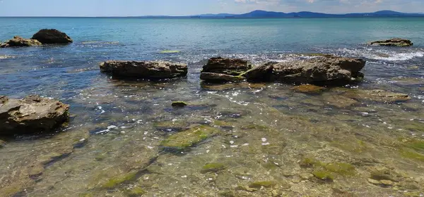 Turkuaz denizin taştan sığ suları. Deniz kıyısında güneşli bir gün.