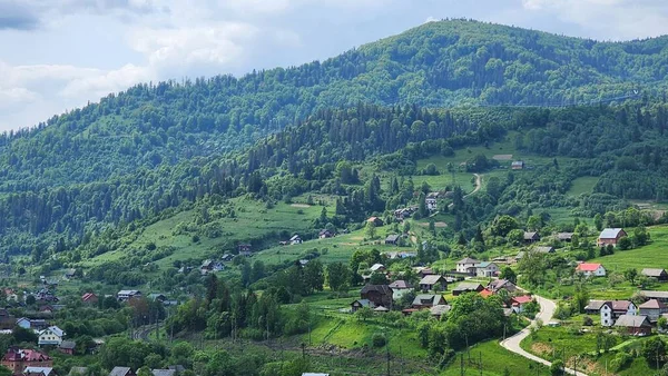 Yoğun ormanlarla kaplı mavi-yeşil dağlardaki bir köy manzarası
