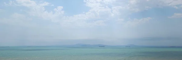 Parlayan bulutlu gökyüzünün altında, turkuaz denizin huzurlu huzuru