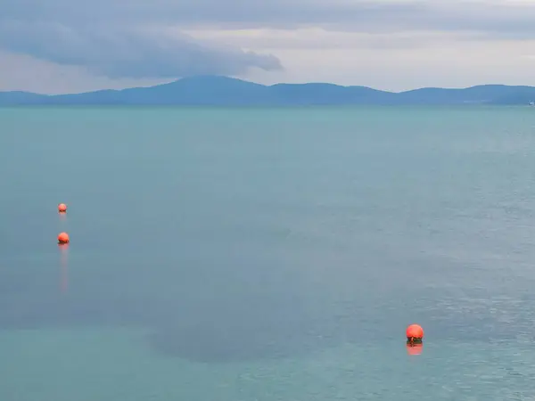 Huzurlu mavi deniz manzarası. Sakin turkuaz deniz yüzeyinde kırmızı şamandıralar