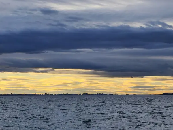 Akşam deniz manzarasında koyu mavi ve sarı bulutların karşıtlığı