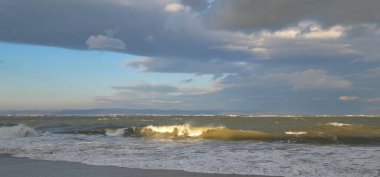 Fırtınalı denizin inanılmaz manzarası. Fırtınalı gökyüzünün altında sarı dalgalar üzerinde beyaz deniz köpüğü tepeleri