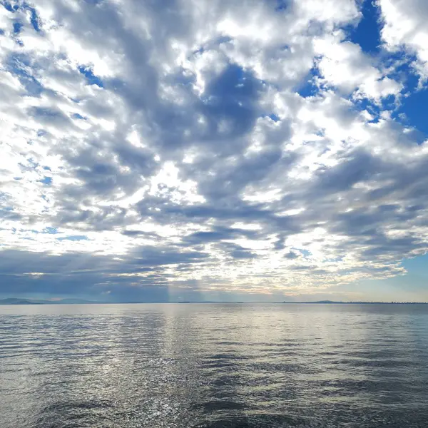 Muhteşem kümülüs bulutları denizin parlak yüzeyine yansıyor.