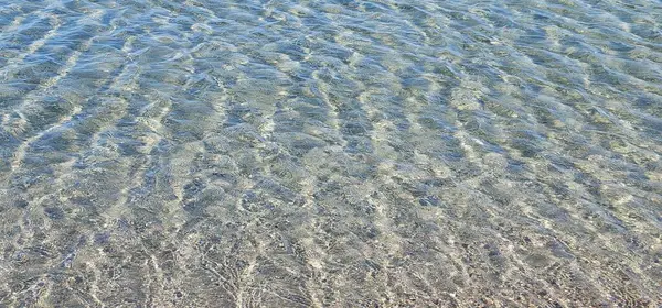 Güneşli bir günde sığ deniz suyunda su ve kum dokusu