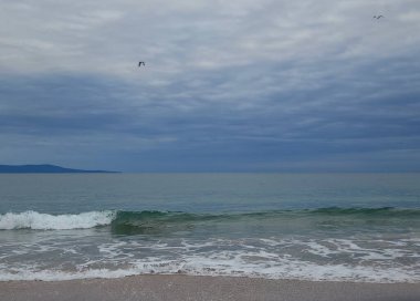 Bulutlu mavi gökyüzü ve akşam deniz manzarasında yeşil deniz