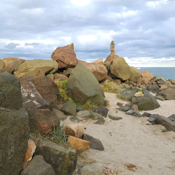 Deniz kıyısındaki kumlu sahilde büyük taşlar. Taştan piramit elle yapılır.