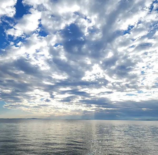 Muhteşem kümülüs bulutları denizin parlak yüzeyine yansıyor.