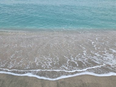 Turkuaz deniz suyunun arka planı ve dantelli köpük kenarlı yumuşak dalgalar.