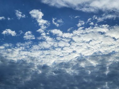 Yumuşak altokümülüs bulutları mavi gökyüzünde güneş tarafından aydınlatılıyor.