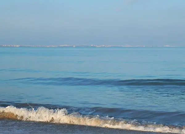 Akşam manzarasında sakin mavi denizin köpüklü kenarı