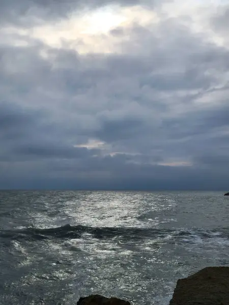 Fırtınalı bir gökyüzünün altında akşam manzarasında çalkantılı çelik renkli bir deniz.