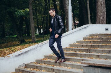 Deri ceketli bir adam merdivenlerden iniyor.