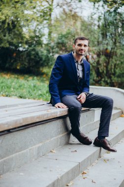 Takım elbiseli bir adam parkta bankta oturuyor.