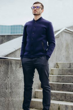 Korkulukların yanında gözlüklü genç bir adam.